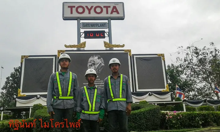 ทีมงานสวมหมวกนิรภัยหน้าอาคารโรงงานโตโยต้า เกตเวย์