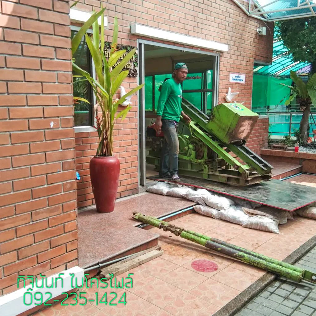 ทีมงานเคลื่อนปั้นจั่นไมโครไพล์ผ่านช่องทางเข้าอาคารภายในโรงเรียน