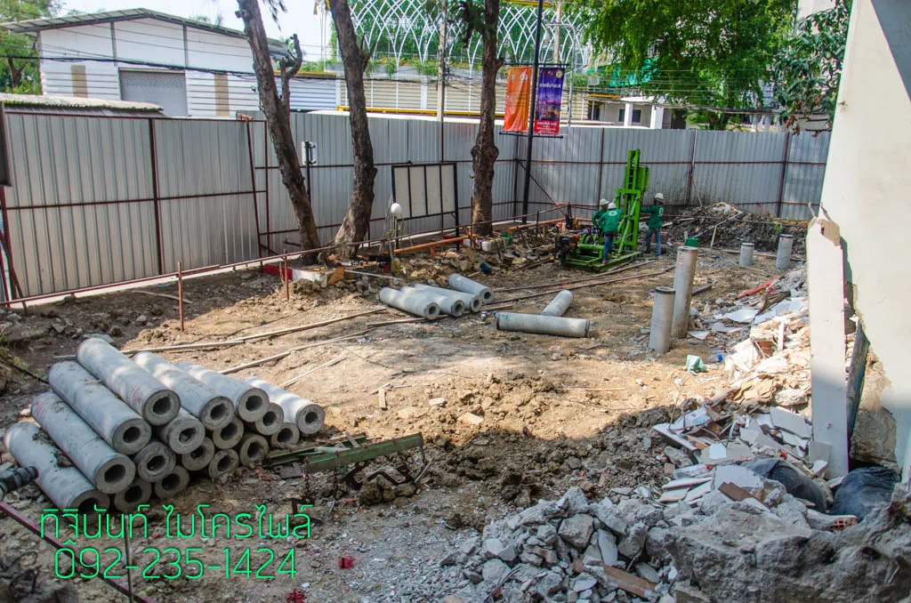 ภาพรวมพื้นที่ก่อสร้างพร้อมปั้นจั่น เสาเข็มที่ตอกแล้ว และกองท่อนเสาเข็ม