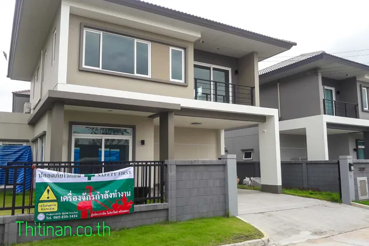 หน้าบ้านวรารมย์ พรีเมี่ยม พร้อมป้ายเตือนเครื่องจักรกำลังทำงานที่รั้ว